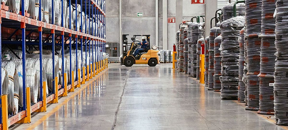 Warehouse aisle with racking and a forklift at work