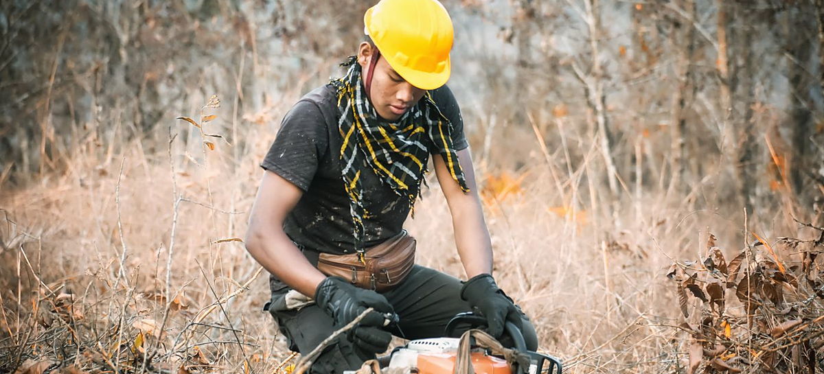 Forestry worker clearing dry brush with a chainsaw