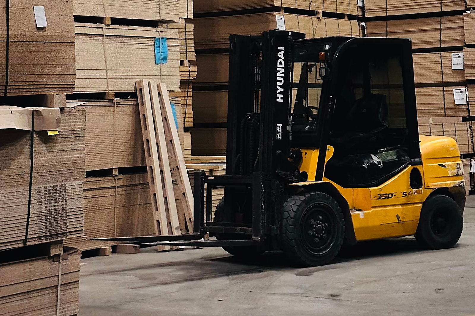 Forklift beside stacked pallets inside a distribution centre